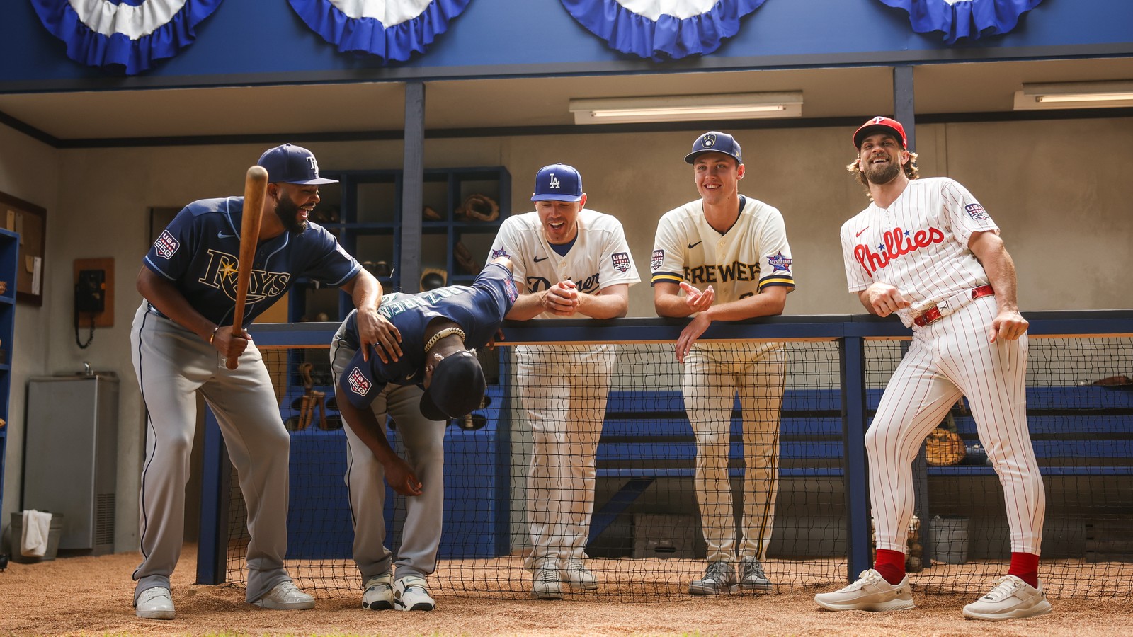 Baseball players from the Rays, Dodgers, Brewers and Phillies laugh in a dugout set built for the Avengers: Doomsday World Series promo
