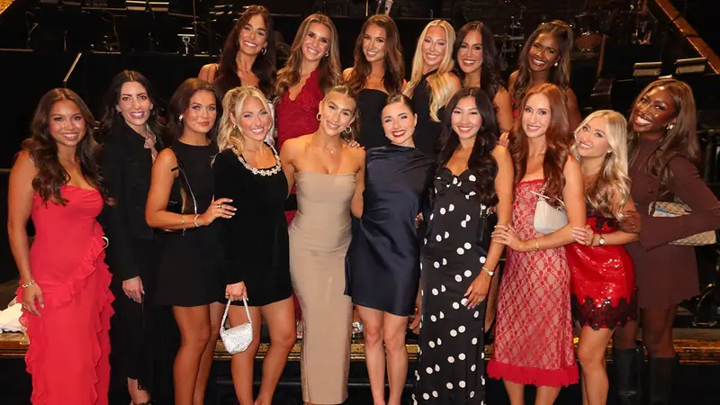 Group photo of 15 women in evening wear posing together, from the Dallas Cowboys Cheerleaders' official website