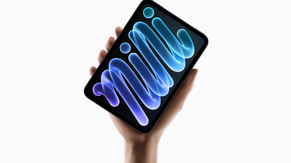 A hand holding the new iPad mini, its OLED screen showing a glowing blue and purple abstract swirl against a white background