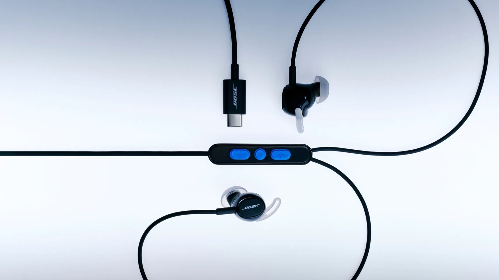 Bose Noise Cancelling Wired Earbuds laid out with USB-C plug and in-line remote on a pale background