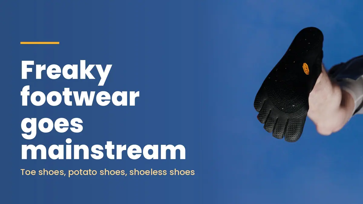 Underside of a black Vibram FiveFingers shoe with separate toes, held up against a blue studio background